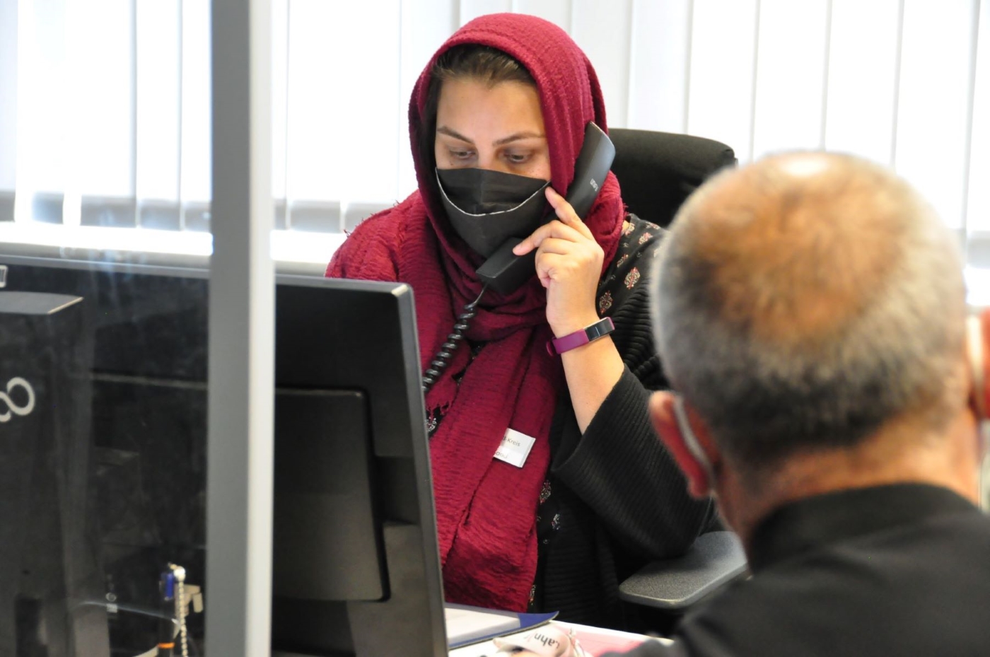 Asfa Masood berät einen Mann aus der Ukraine während der Sprechzeit im Flüchtlingsbüro. Er benötigt einen Arzttermin. Foto: Lahn-Dill-Kreis