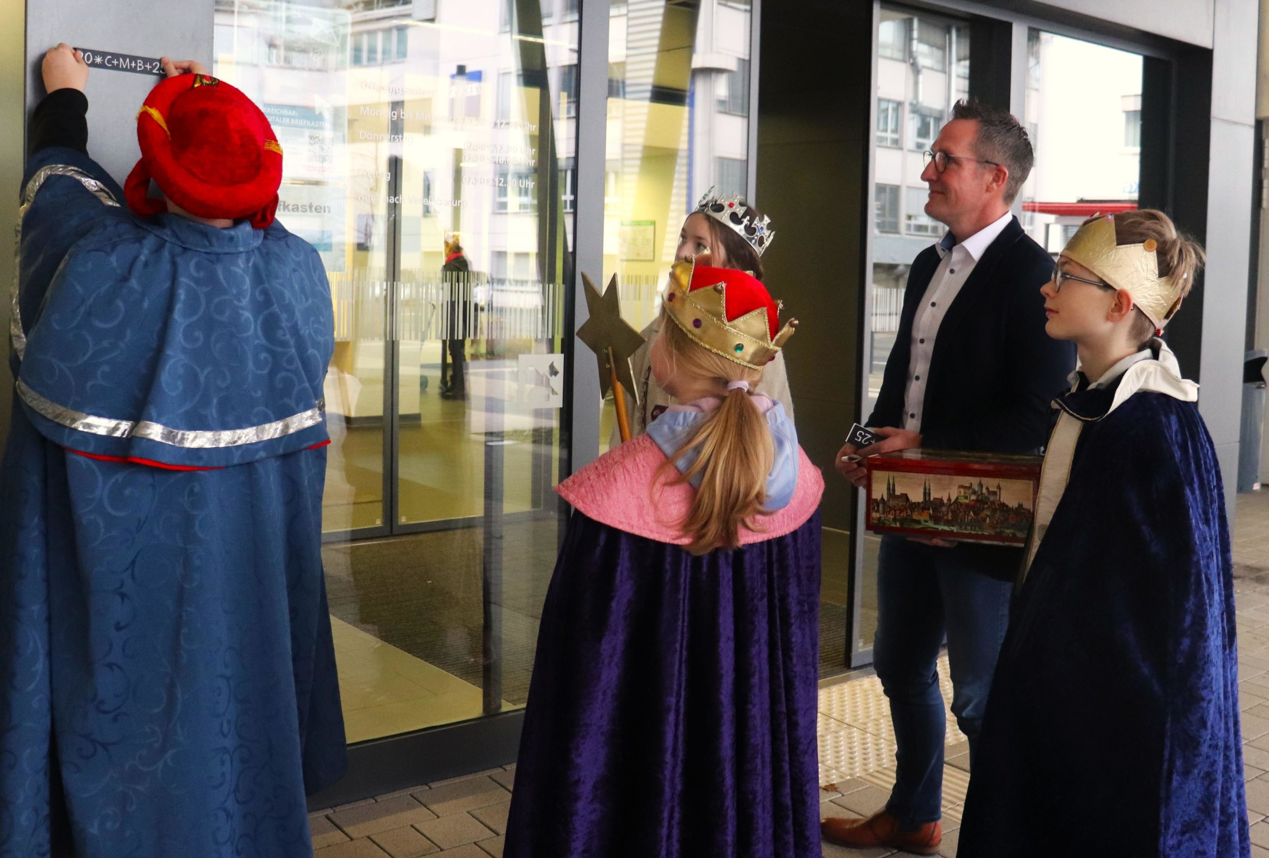 Zum Abschluss ihres Besuches bringen die Sternsinger den Segensspruch am Haupteingang des Kreishauses in Wetzlar an. Foto: Lahn-Dill-Kreis